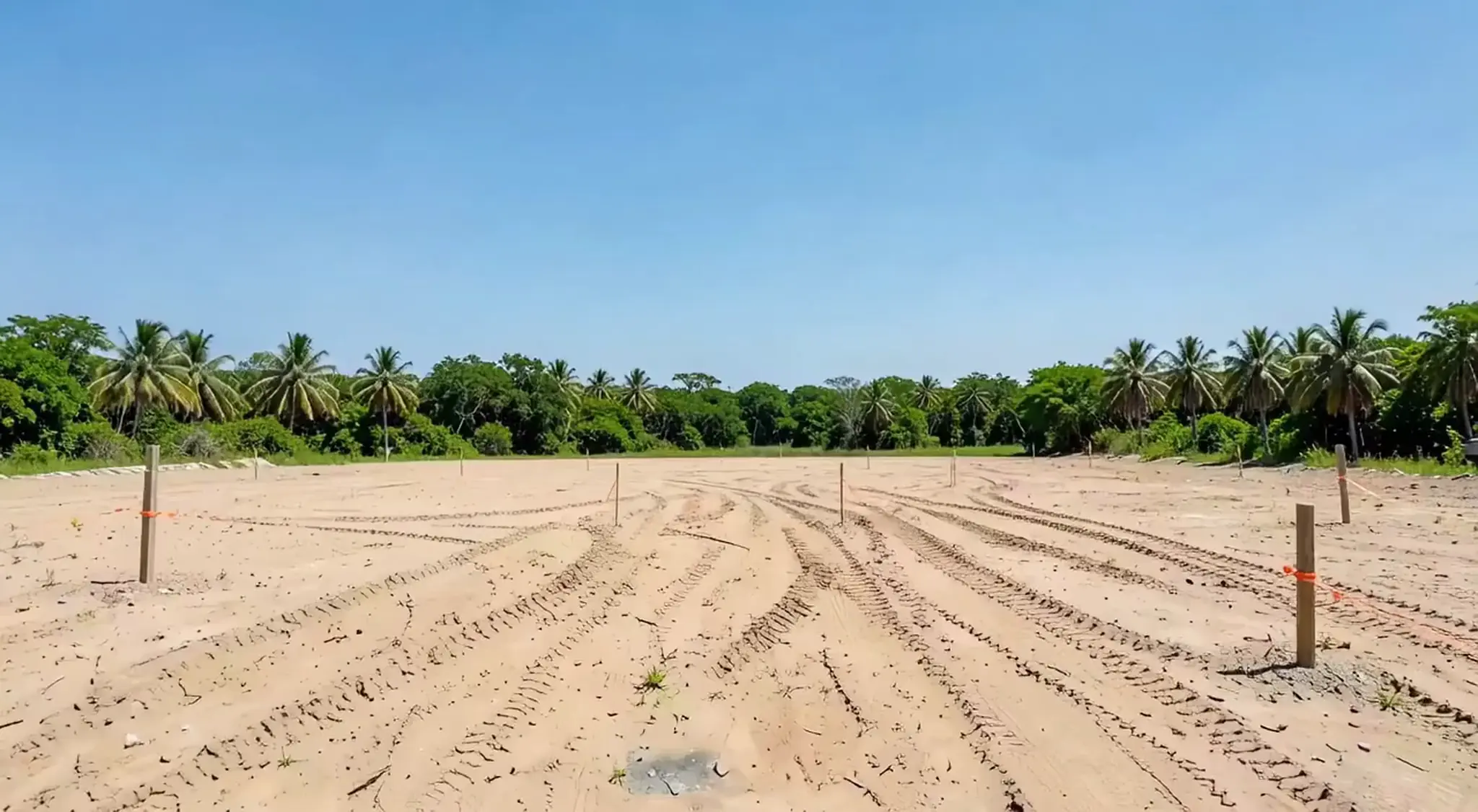 An empty sand lot with survey stakes under a blue Florida sky, the first frame of the build film (illustrative, generated).